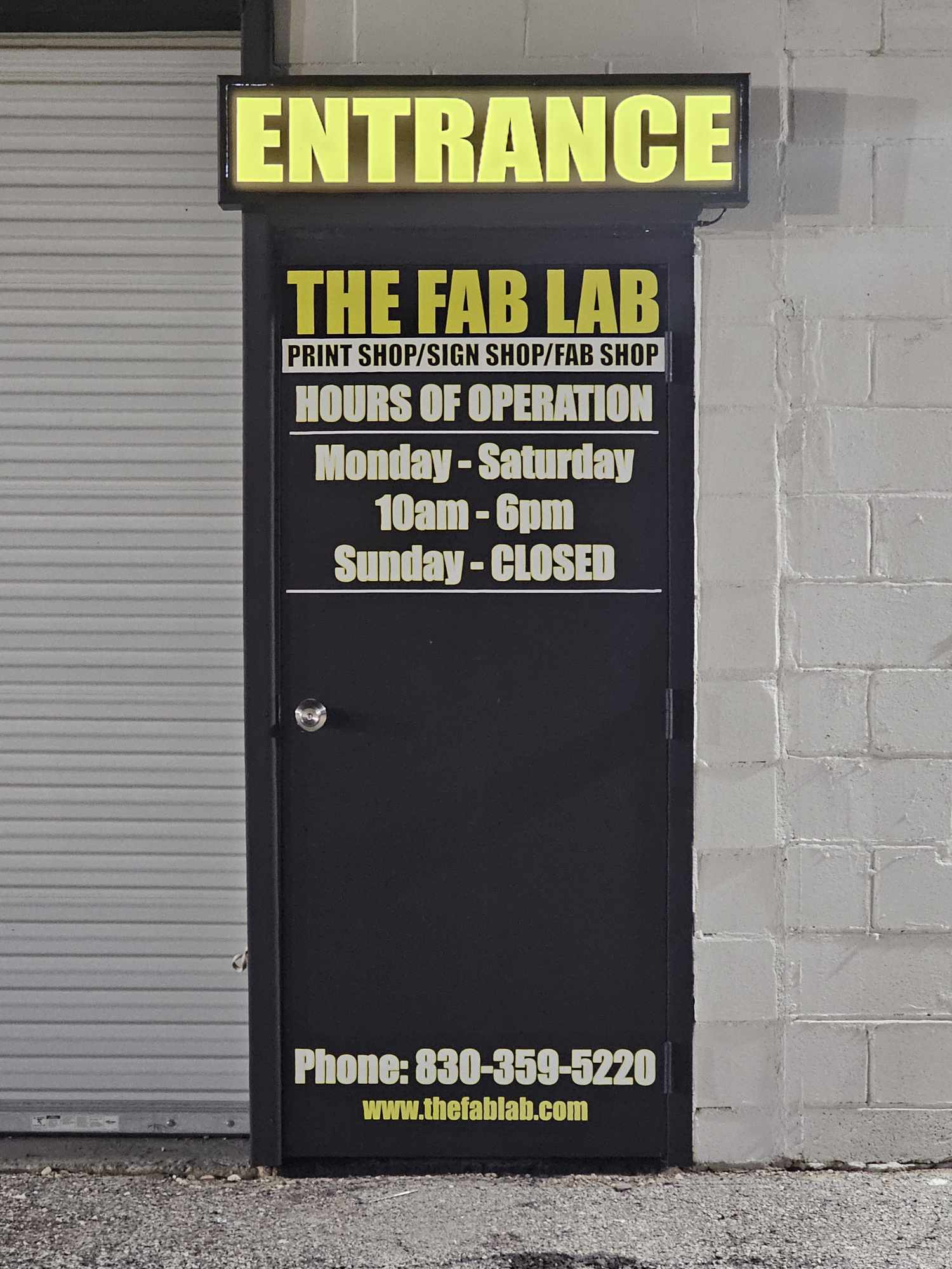 The entrance to The Fab Lab featuring a black door with business hours, contact information, and services listed.